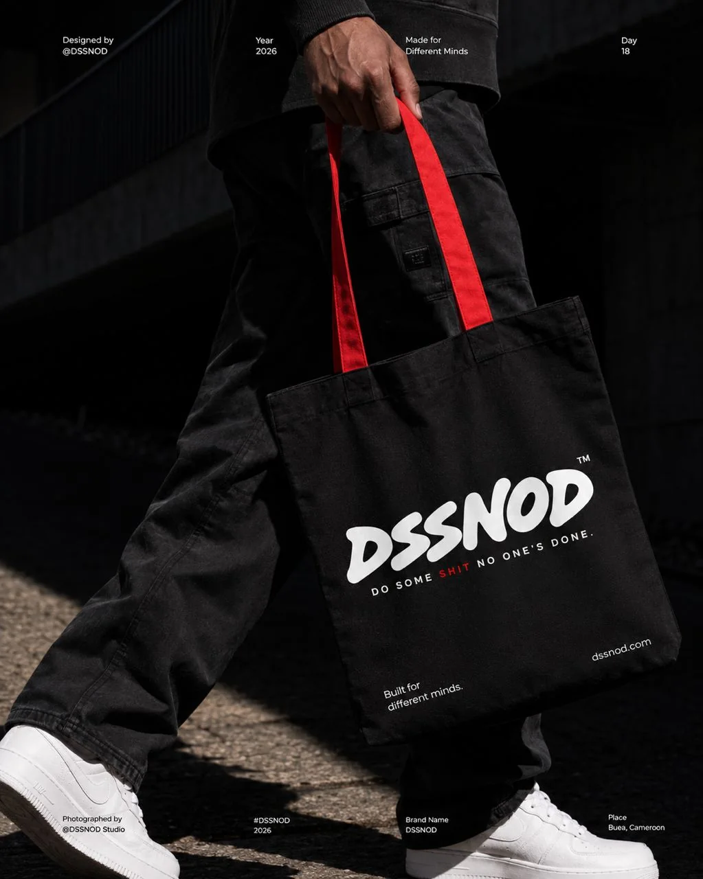A person carrying a black DSSNOD tote bag with red handles