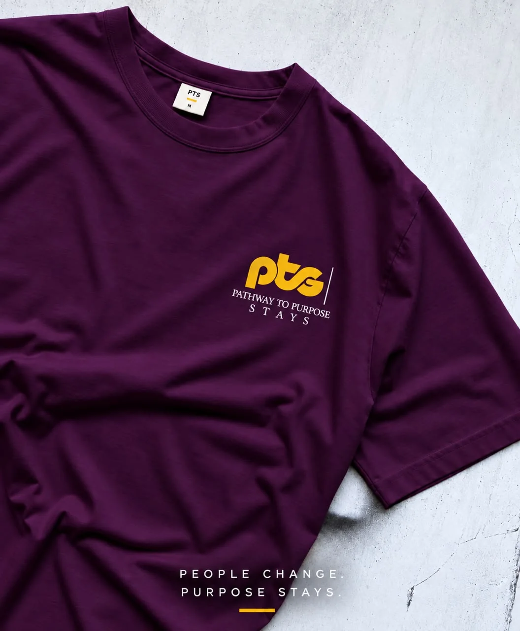 A plum t-shirt with a small yellow PTS logo on the chest